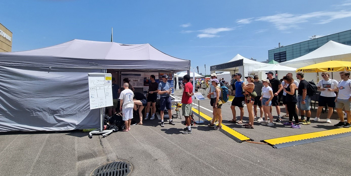 Menschen stehen vor einem Ausstellungsstand Schlange.