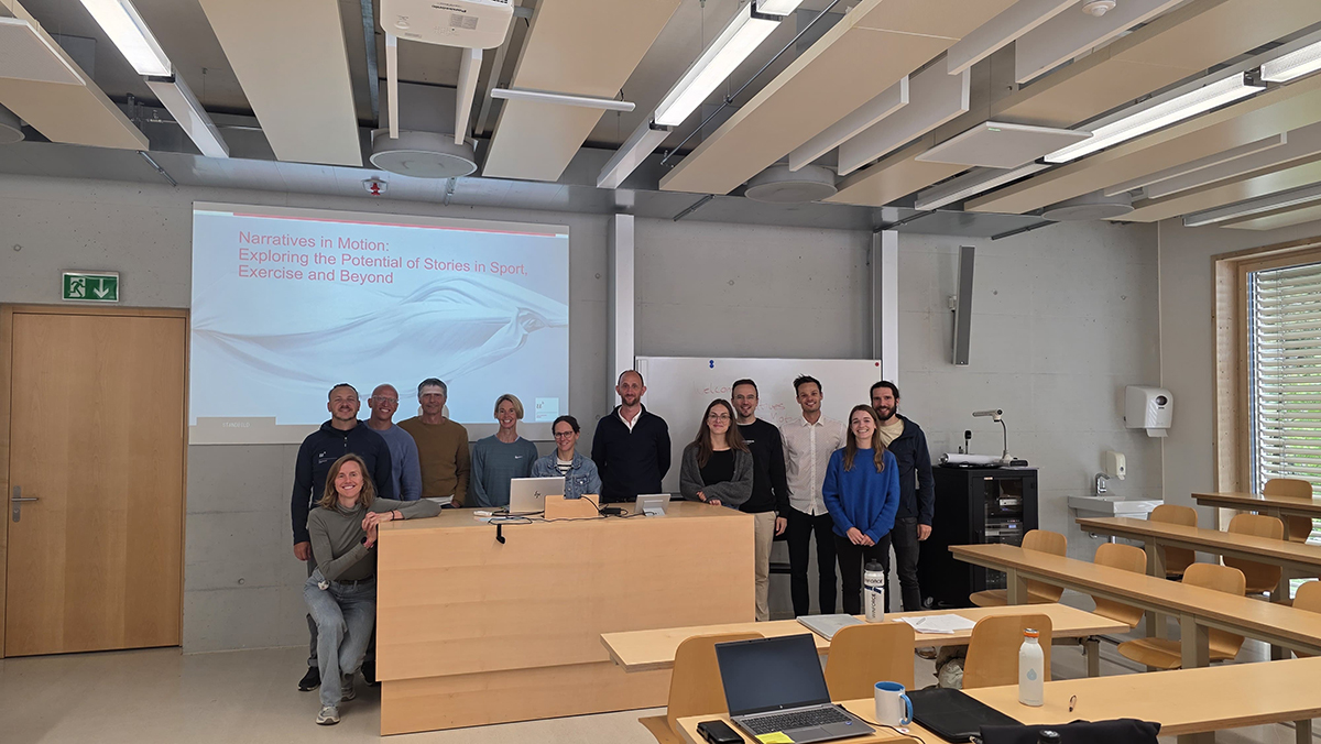 Symposium-Teilnehmende stehen vor der projezierten Titelfolie des Symposiums.